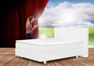 Eine Frau steht vor einem Bett, umgeben von einem roten Vorhang.